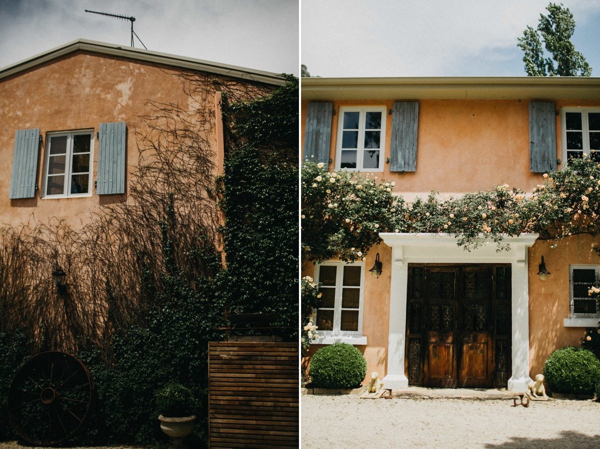 A country homestead stands amid trees and flowering shrubs. Photograph by documentary wedding photographer Joshua Mikhaiel.