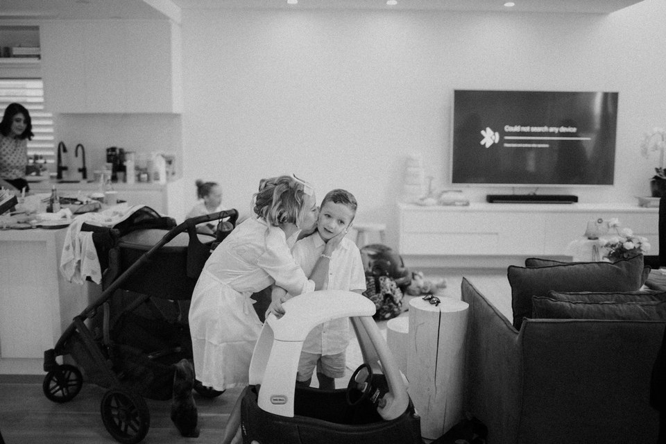 A young child sits with an adult in a bright living room. Photograph by documentary wedding photographer Joshua Mikhaiel.