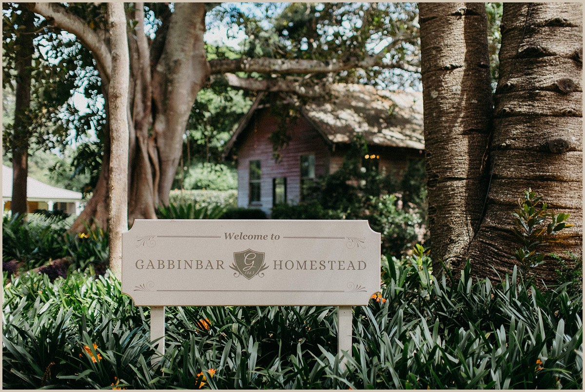Gabbinbar Homestead entrance sign — Joshua Mikhaiel, documentary wedding photographer A wooden sign marks the entrance to Gabbinbar Homestead among the garden trees. Photograph by documentary wedding photographer Joshua Mikhaiel.
