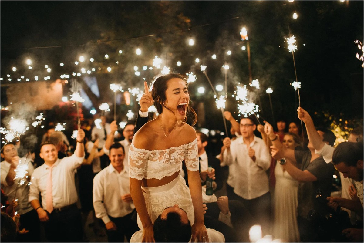 Dancing beneath the lights — Joshua Mikhaiel, documentary wedding photographer A bride dances beneath string lights as wedding guests cheer around her. Photograph by documentary wedding photographer Joshua Mikhaiel.