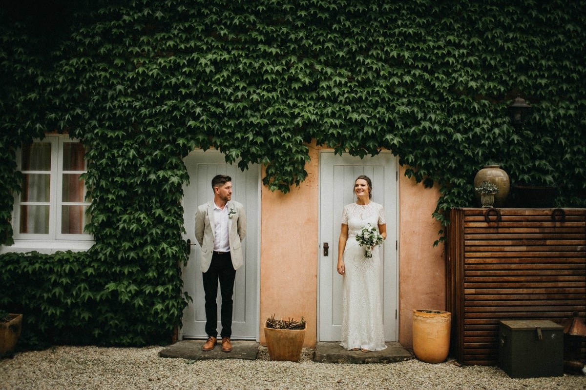 The newlyweds pose together outside the ivy-covered homestead. Photograph by documentary wedding photographer Joshua Mikhaiel.