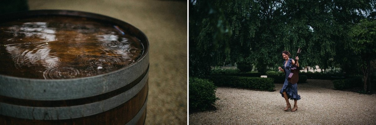 The bride and groom walk outside in a rainy garden scene. Photograph by documentary wedding photographer Joshua Mikhaiel.