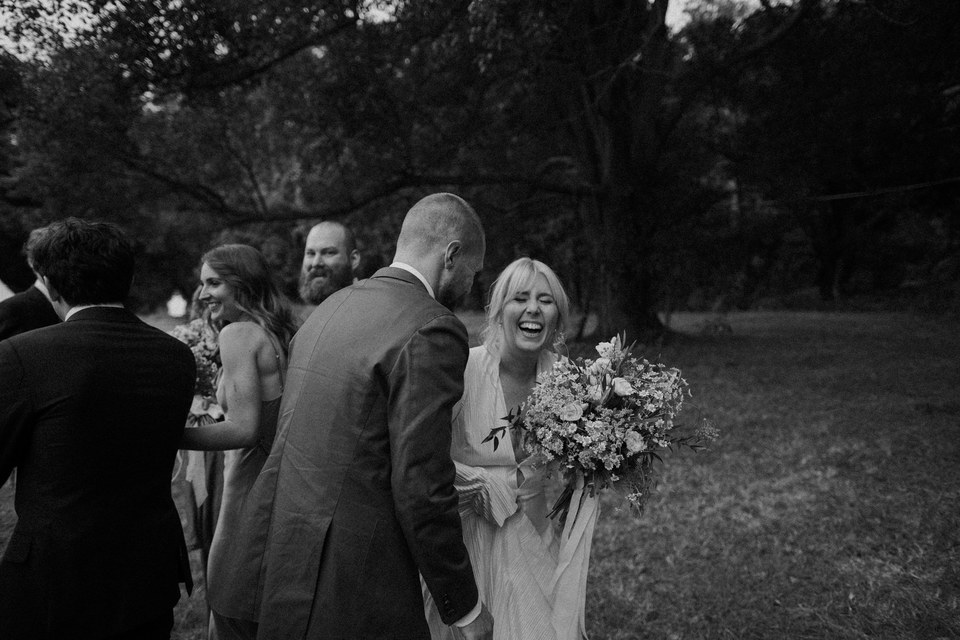 A bride and groom laugh with guests after the ceremony, in a black-and-white photograph. Photograph by documentary wedding photographer Joshua Mikhaiel.