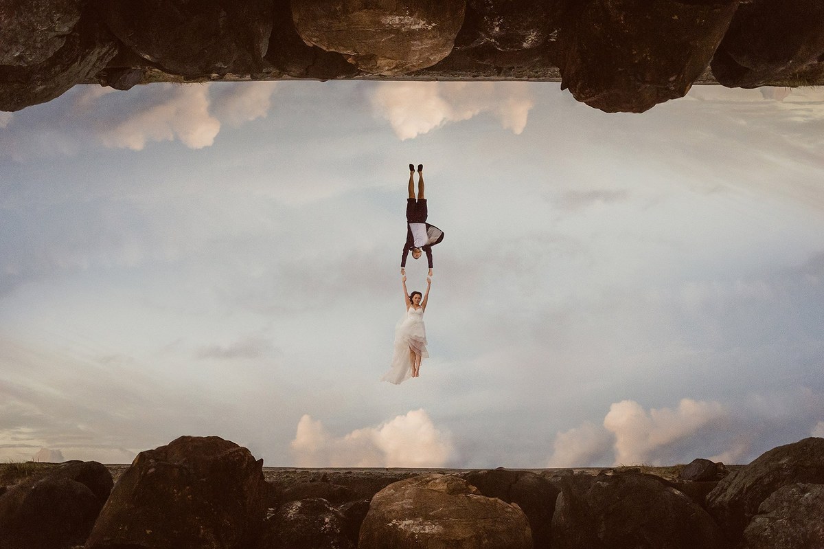 A person performs a handstand inside a rocky sea cave.