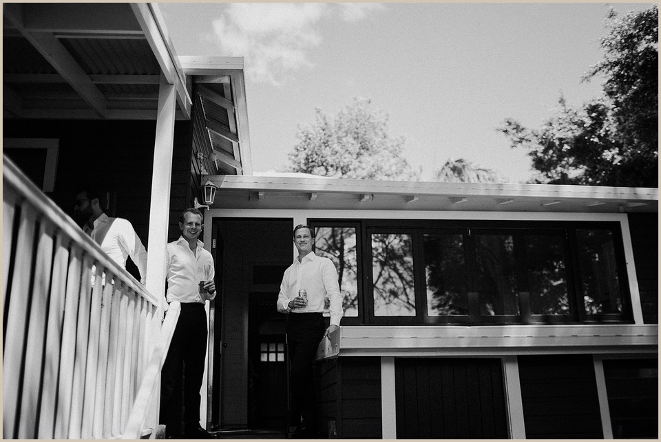 A black-and-white view shows a couple standing together on the veranda. Photograph by documentary wedding photographer Joshua Mikhaiel.