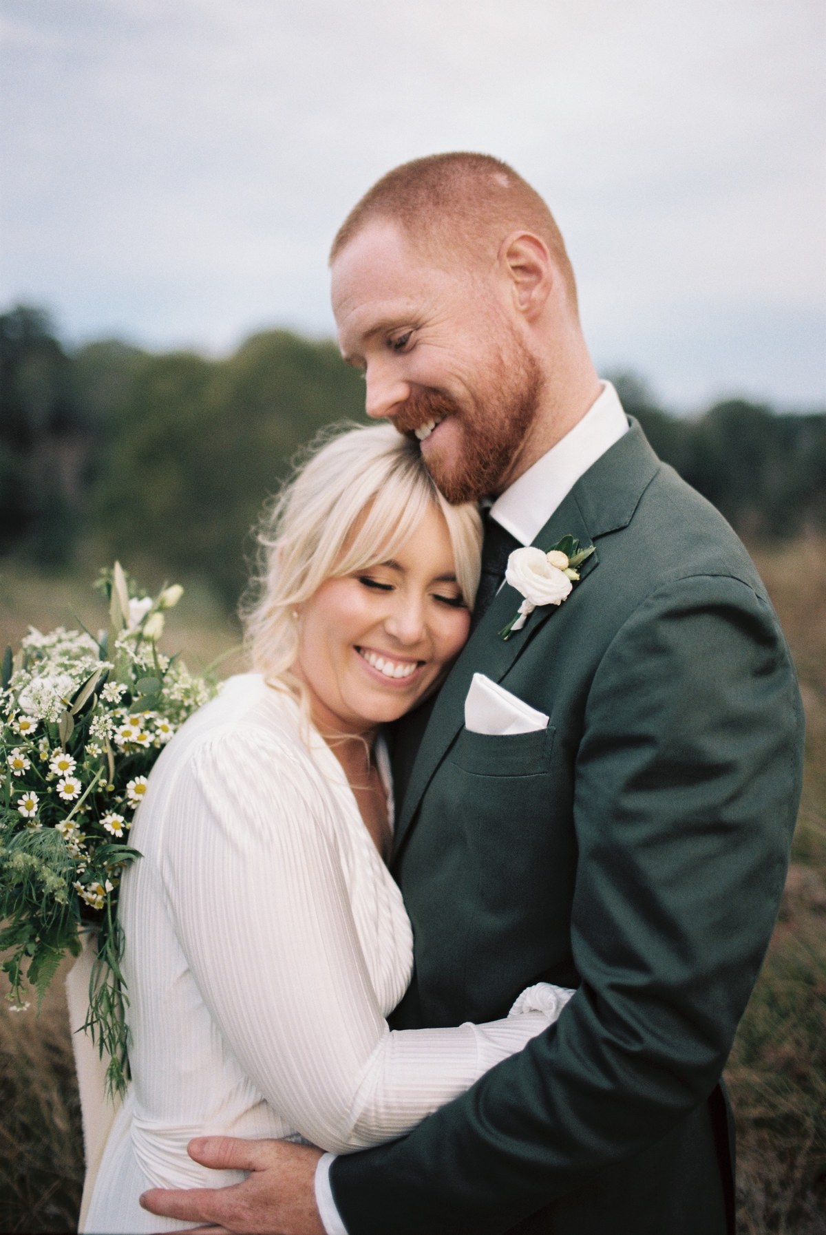 A smiling bride and groom hold one another close outdoors. Photograph by documentary wedding photographer Joshua Mikhaiel.