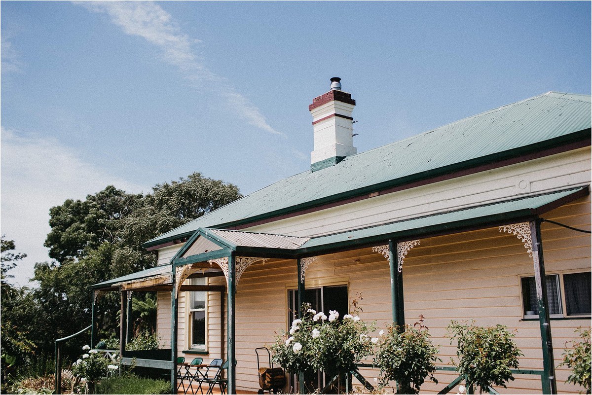 A timber lodge sits at the edge of the forest beneath a clear sky, photographed by documentary wedding photographer Joshua Mikhaiel.