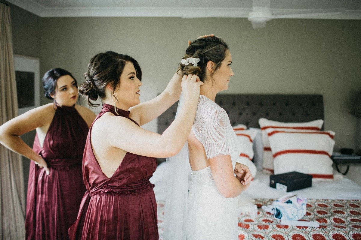 Two guests lift the bride playfully in the garden. Photograph by documentary wedding photographer Joshua Mikhaiel.