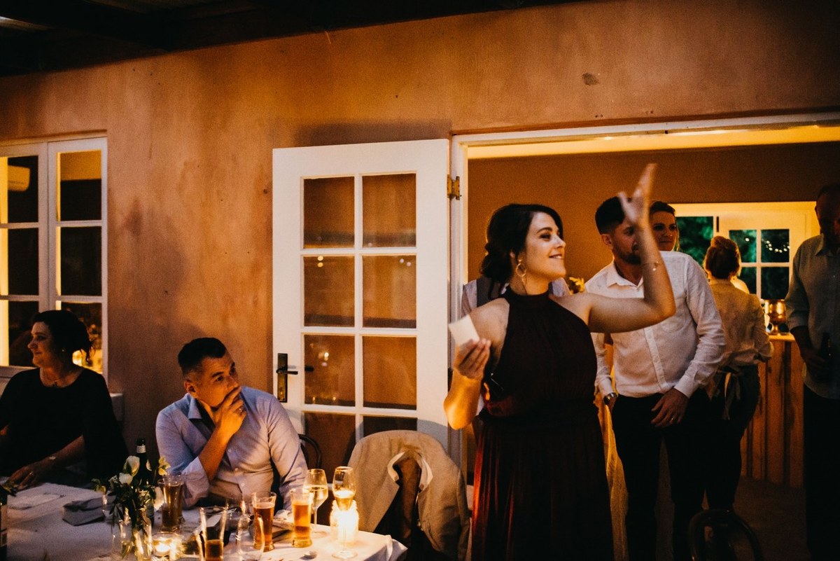 A guest holds a microphone while seated guests listen. Photograph by documentary wedding photographer Joshua Mikhaiel.