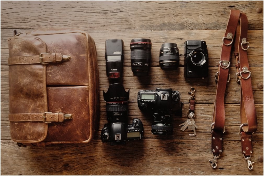 Camera equipment laid out on a table at Carriageworks, Sydney — Joshua Mikhaiel, documentary wedding photographer A camera bag, lenses and straps are laid out on a wooden surface, photographed by documentary wedding photographer Joshua Mikhaiel.