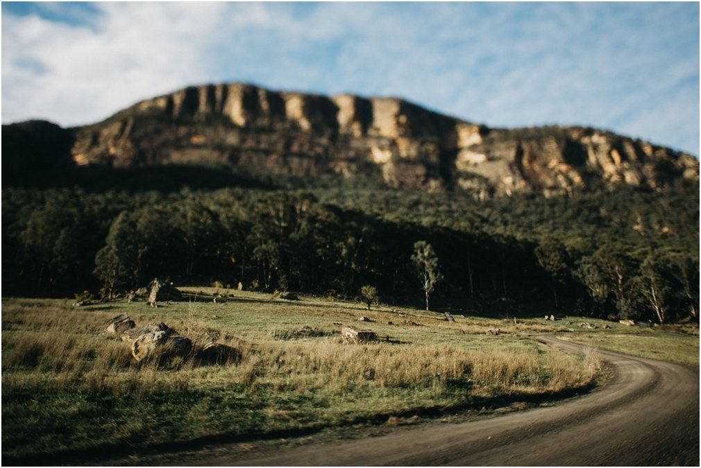 Rocky cliff above the valley — Joshua Mikhaiel, documentary wedding photographer A rocky cliff rises above an open valley in Australia, photographed by documentary wedding photographer Joshua Mikhaiel.