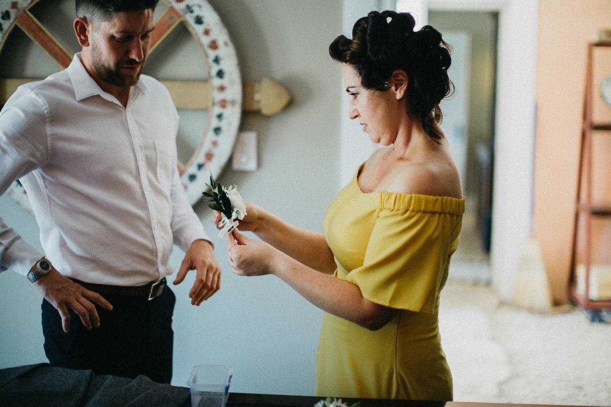 The groom helps a guest adjust her dress before the ceremony. Photograph by documentary wedding photographer Joshua Mikhaiel.
