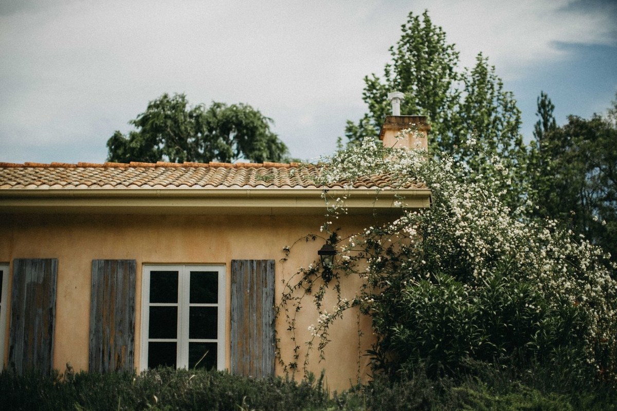 A cottage with timber shutters stands among the trees. Photograph by documentary wedding photographer Joshua Mikhaiel.