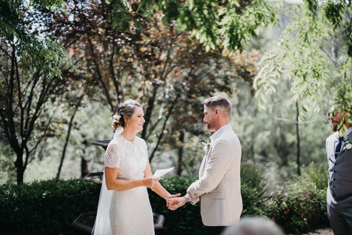 The bride and groom hold hands during the ceremony as guests watch. Photograph by documentary wedding photographer Joshua Mikhaiel.