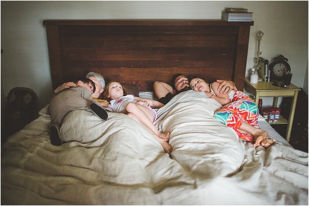 The Henderson family together at home — Joshua Mikhaiel, documentary wedding photographer A family lies together on a large bed in their bedroom, photographed by documentary photographer Joshua Mikhaiel.