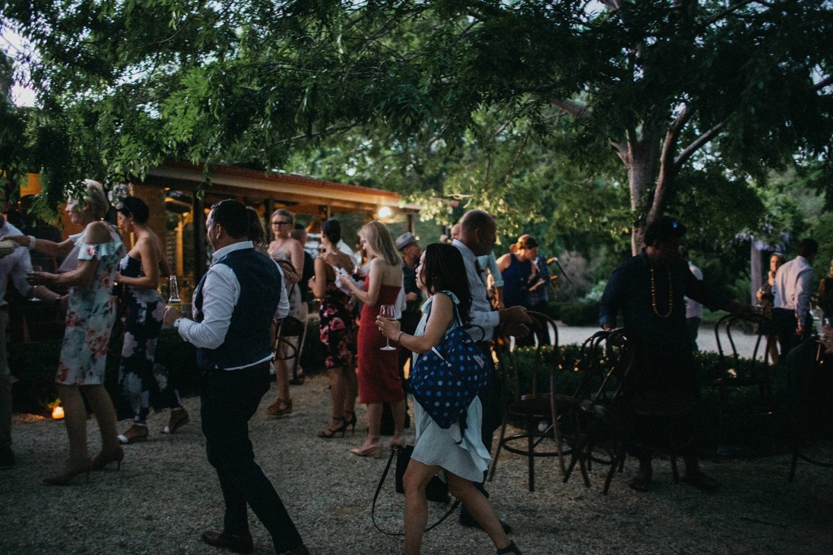 Guests mingle outdoors beside the reception building after dark. Photograph by documentary wedding photographer Joshua Mikhaiel.