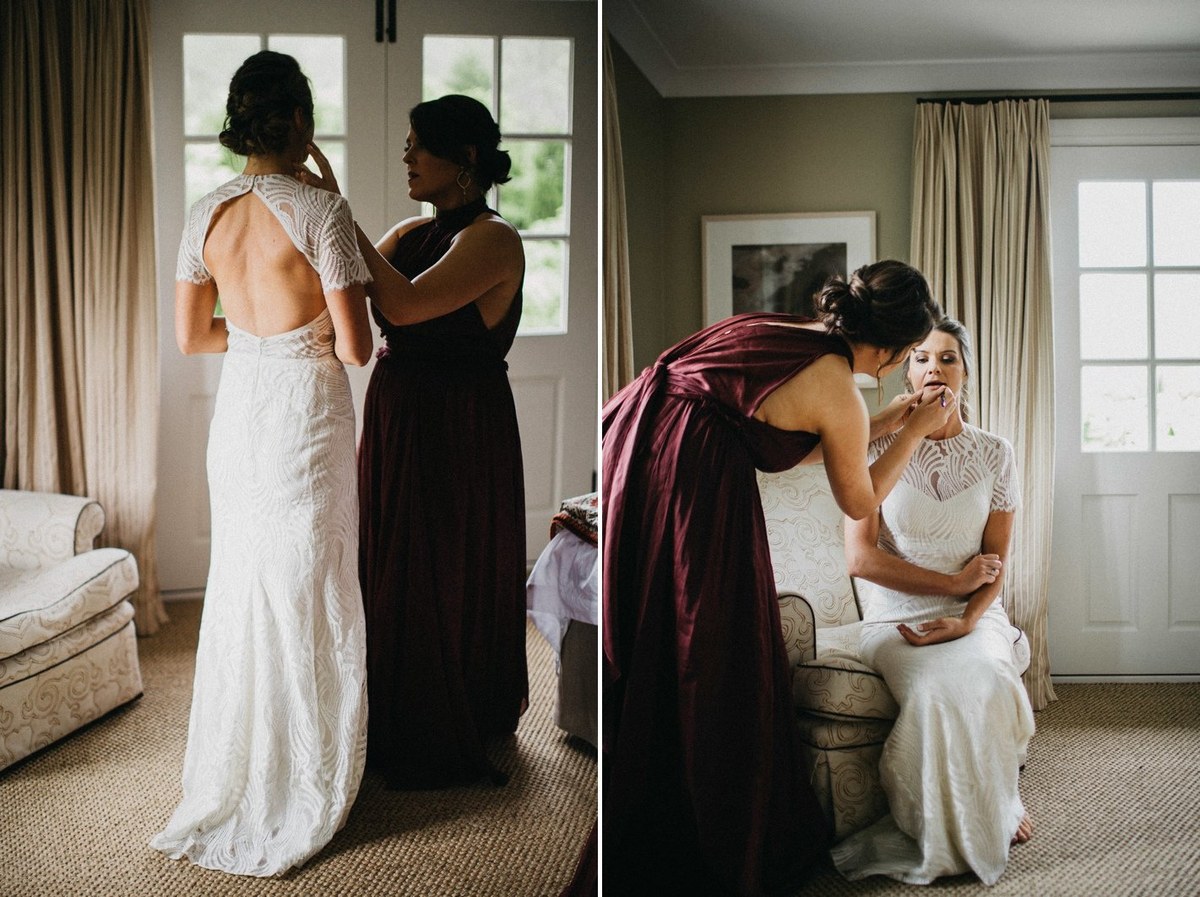 The bride stands as an attendant adjusts the back of her dress. Photograph by documentary wedding photographer Joshua Mikhaiel.