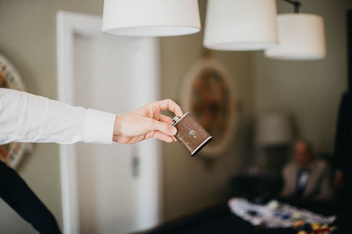 A man pins a boutonniere onto the groom’s jacket. Photograph by documentary wedding photographer Joshua Mikhaiel.