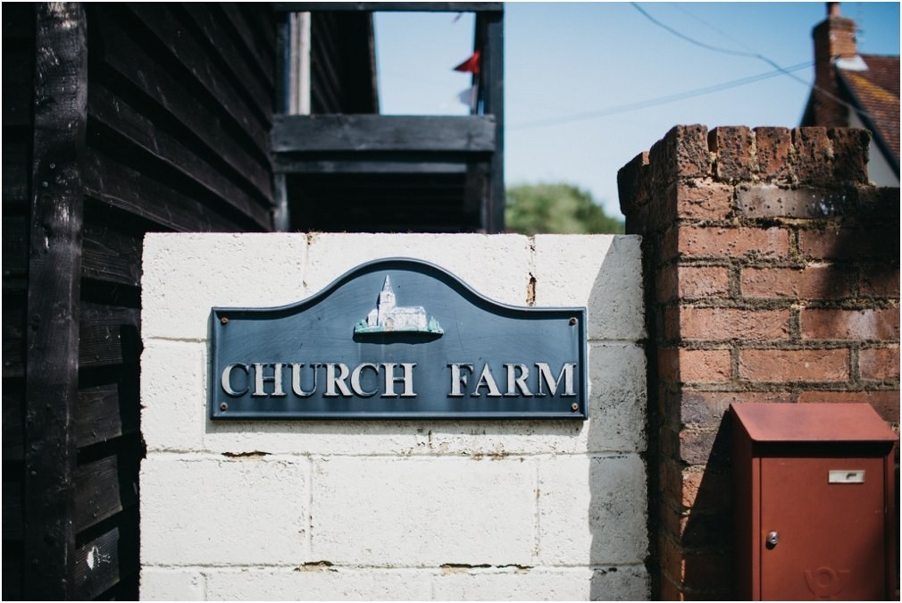 Church Farm entrance sign — Joshua Mikhaiel, documentary wedding photographer A sign for Church Farm is fixed to a white stone wall beside the entrance, photographed by documentary wedding photographer Joshua Mikhaiel.