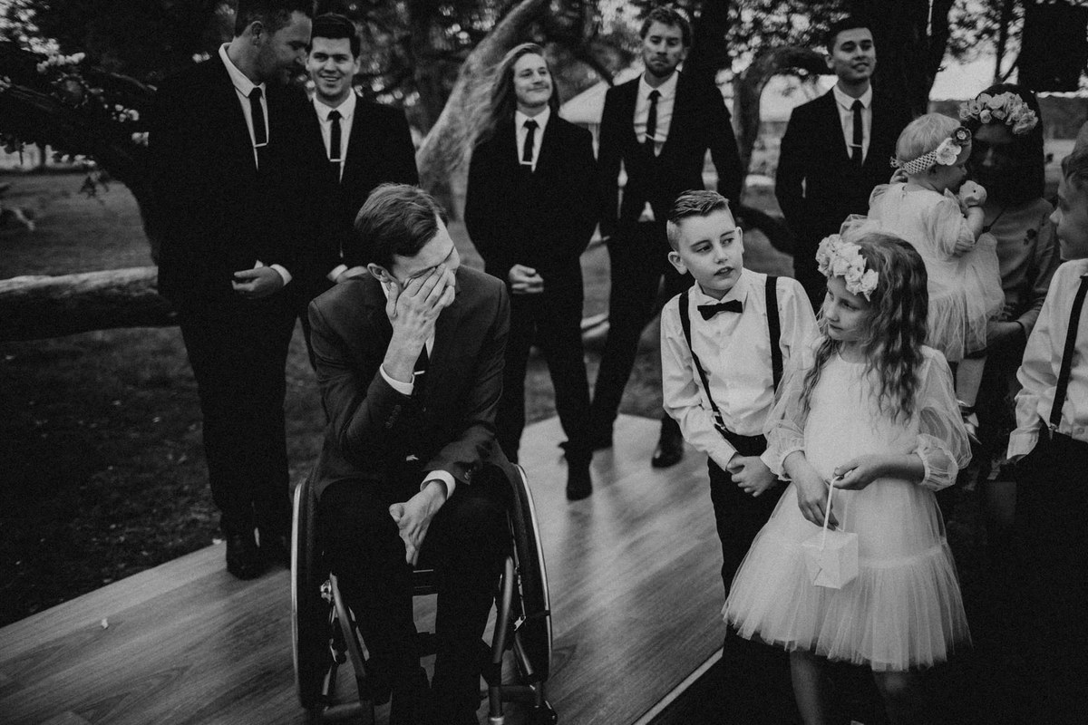 Wedding guests cheer as a groom dances beside the bride in a black-and-white photograph by Joshua Mikhaiel.
