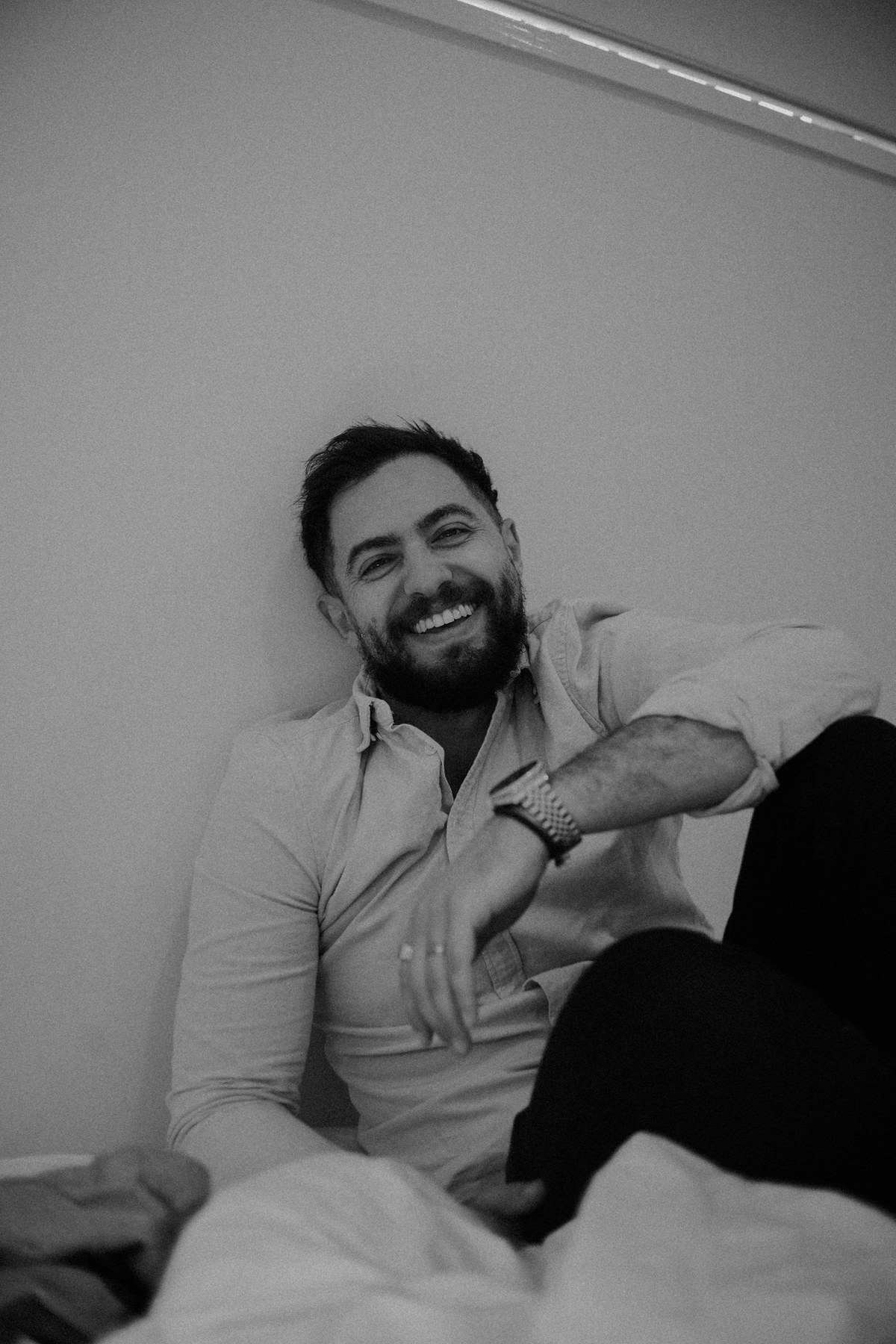 Documentary wedding photographer Joshua Mikhaiel sits smiling in a relaxed portrait.
