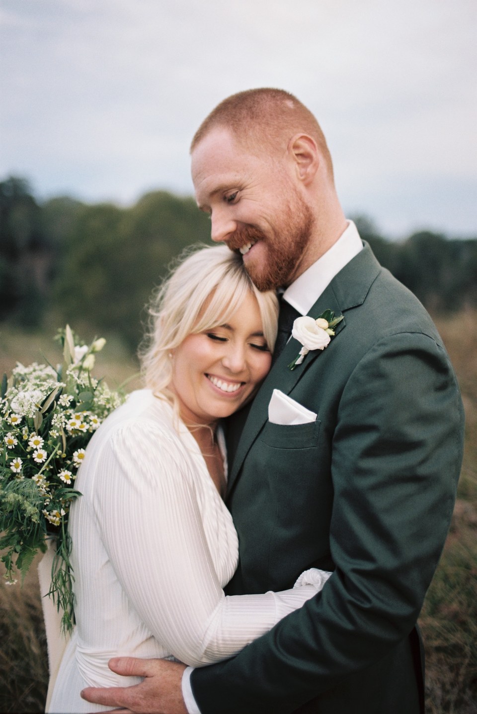 A smiling bride and groom hold one another close outdoors. Photograph by documentary wedding photographer Joshua Mikhaiel.
