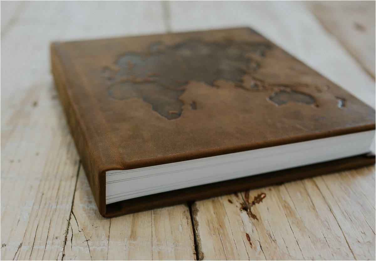 Leather wedding album — Joshua Mikhaiel, documentary wedding photographer A leather-bound wedding album rests on a pale wooden surface. Photograph by documentary wedding photographer Joshua Mikhaiel.