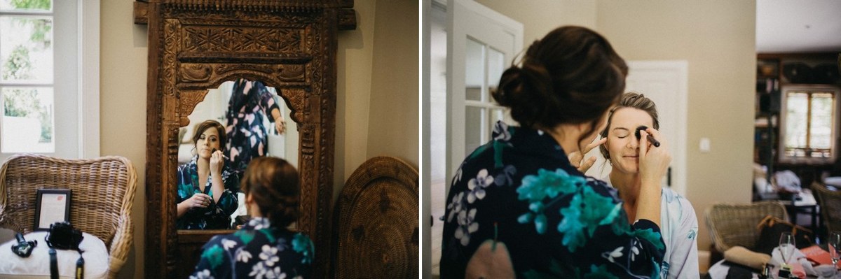 The bride gets ready before a mirror as an attendant works on her hair. Photograph by documentary wedding photographer Joshua Mikhaiel.