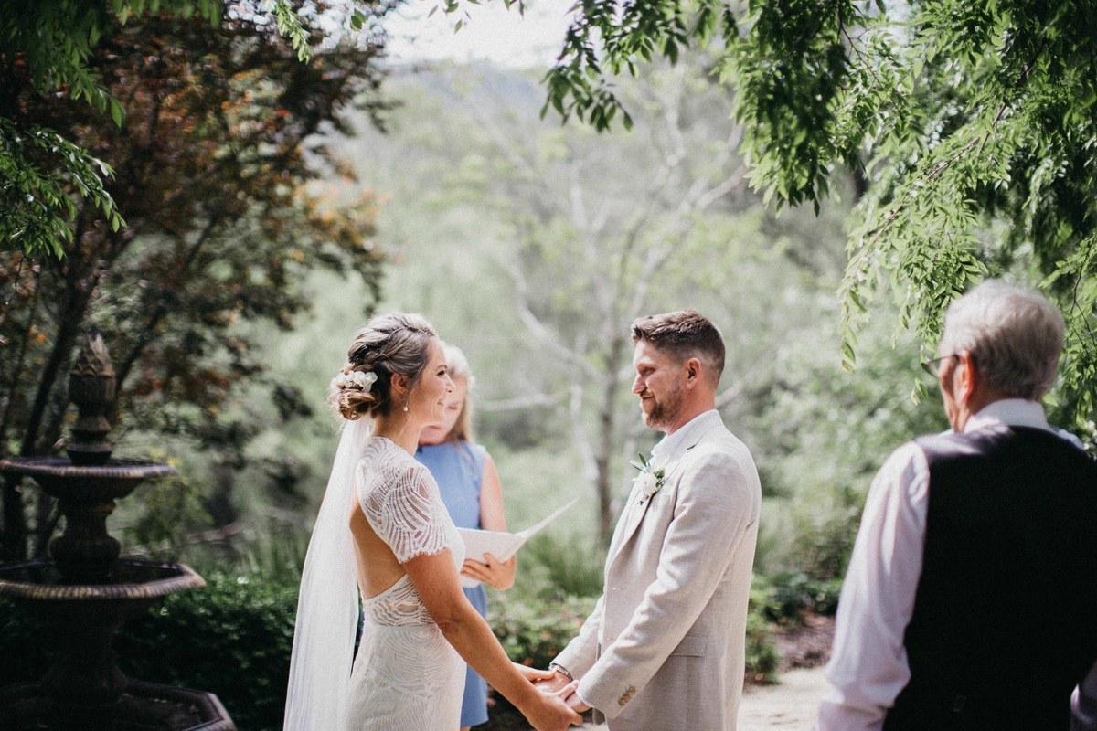 The bride and an older guest hold hands as another guest looks on. Photograph by documentary wedding photographer Joshua Mikhaiel.