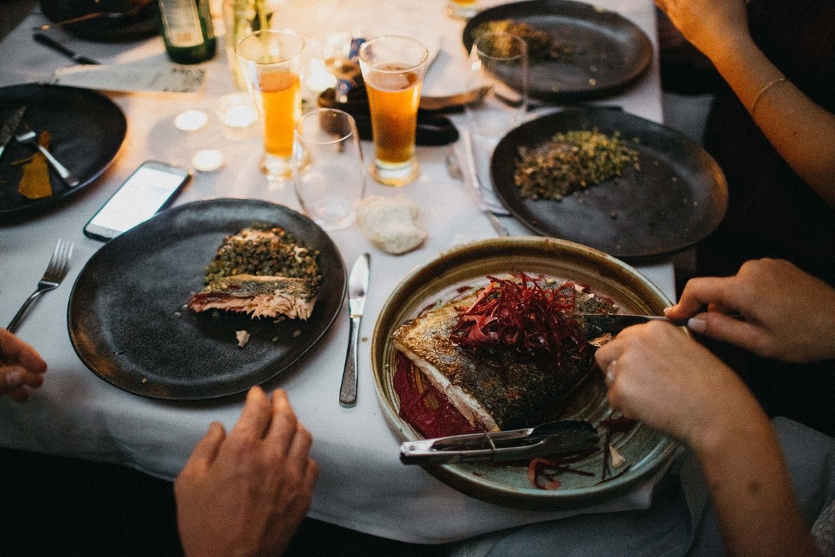 Guests eat and talk at candlelit tables in a two-photo collage. Photograph by documentary wedding photographer Joshua Mikhaiel.