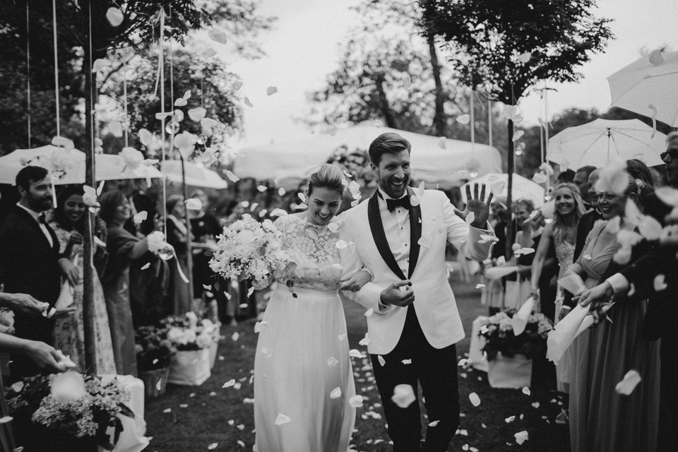 A couple and wedding guests laugh together in a black-and-white photograph. Photograph by documentary wedding photographer Joshua Mikhaiel.