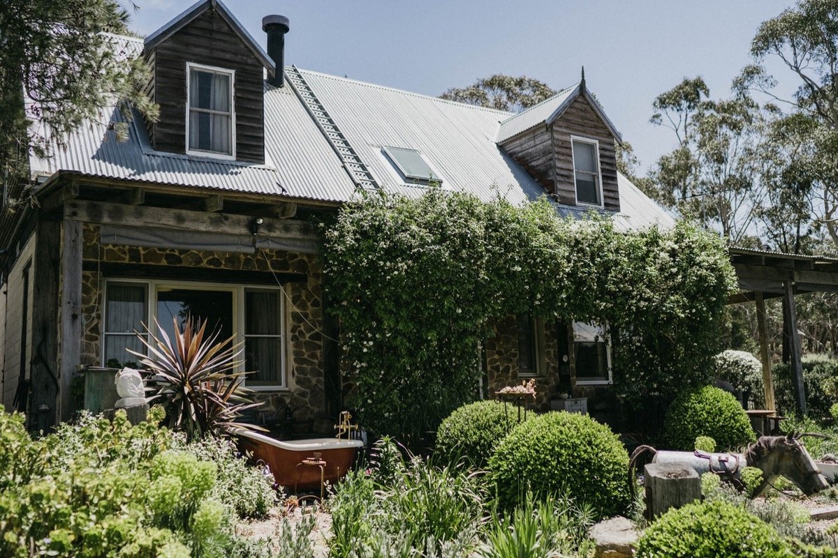A country house stands among garden trees and flowering shrubs, photographed by documentary wedding photographer Joshua Mikhaiel.