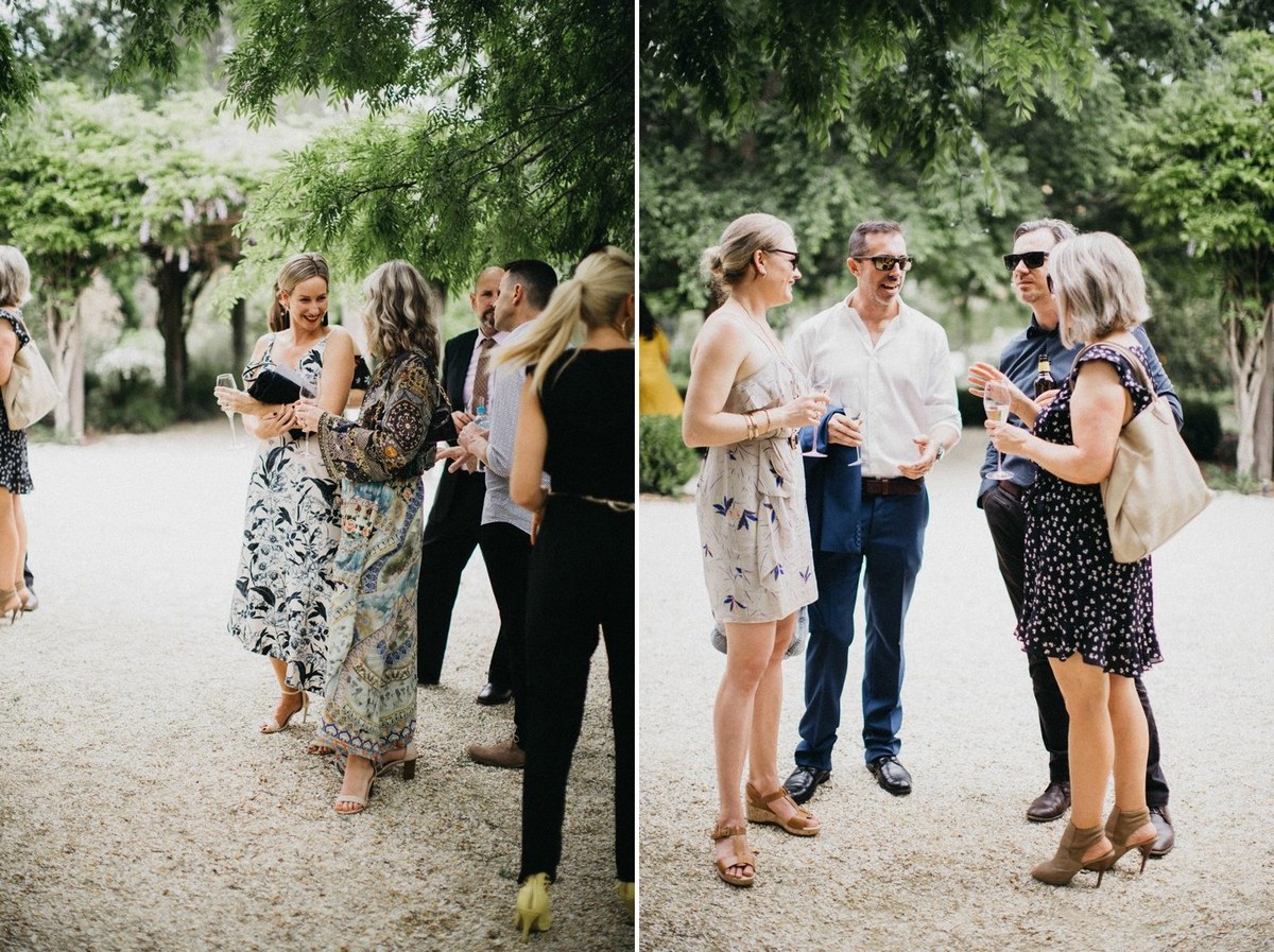 Two guests speak together beneath the trees before the ceremony. Photograph by documentary wedding photographer Joshua Mikhaiel.