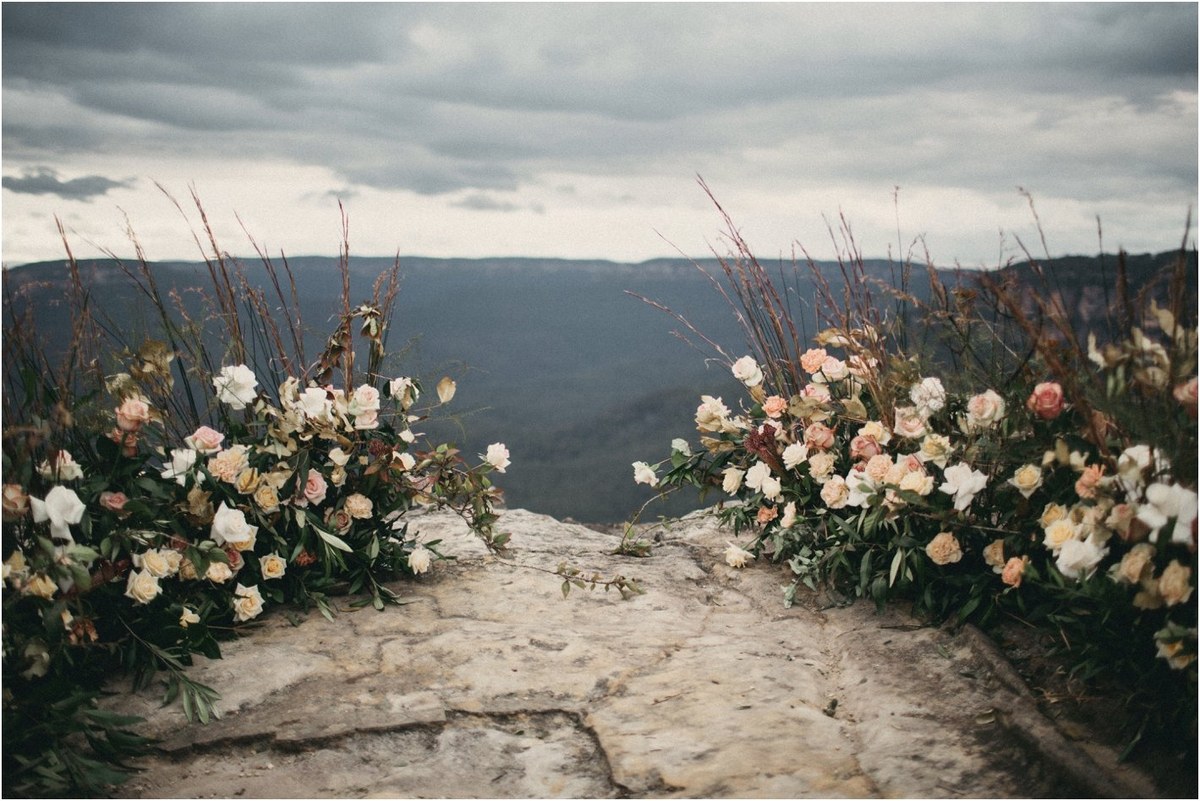 A wedding arch decorated with flowers overlooks the mountain valley. Photograph by documentary wedding photographer Joshua Mikhaiel.