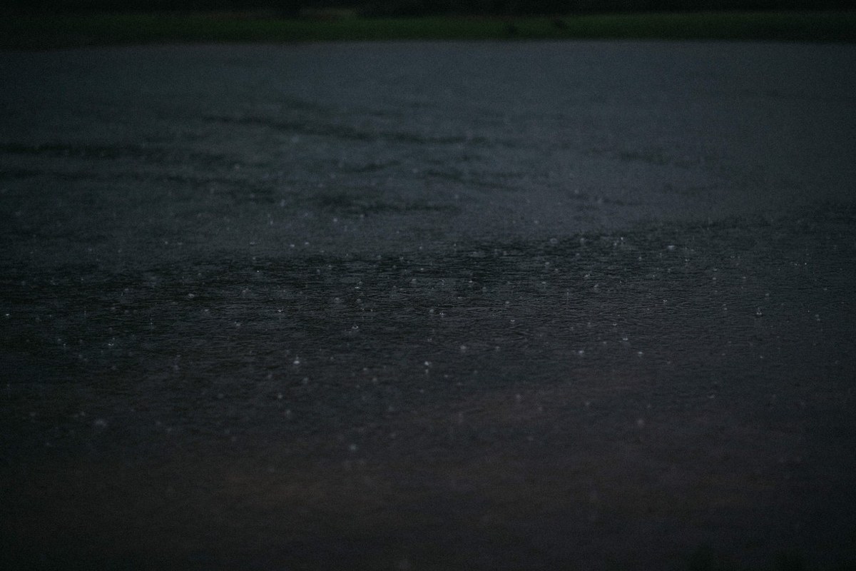 A dark water surface reflects faint light after the rain. Photograph by documentary wedding photographer Joshua Mikhaiel.