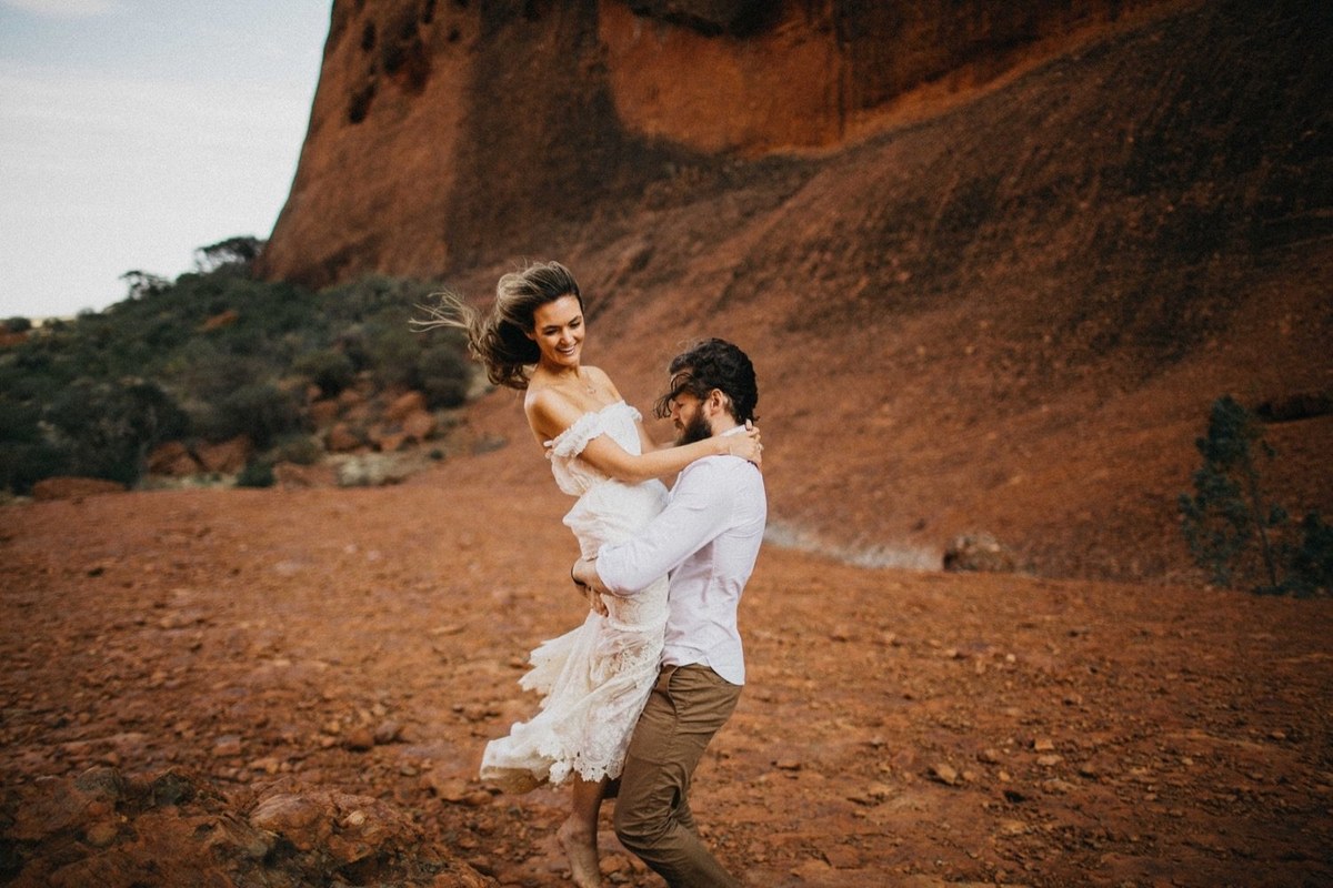 A bride lifts her partner in a red-rock landscape, photographed by documentary wedding photographer Joshua Mikhaiel.