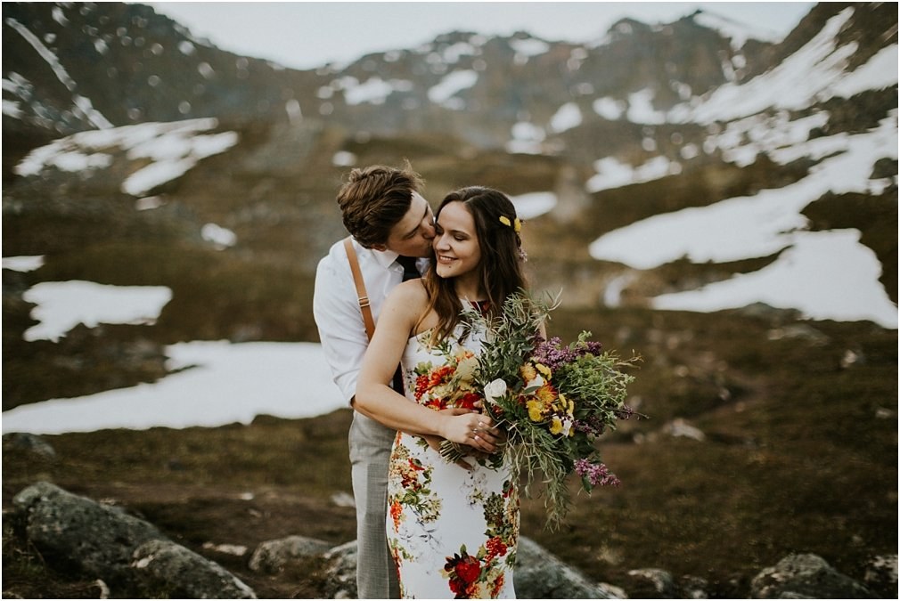 Couple on a snowy alpine slope in Alaska — Joshua Mikhaiel, documentary wedding photographer The bride and groom stand together on a rocky alpine slope with patches of snow, photographed by documentary wedding photographer Joshua Mikhaiel.